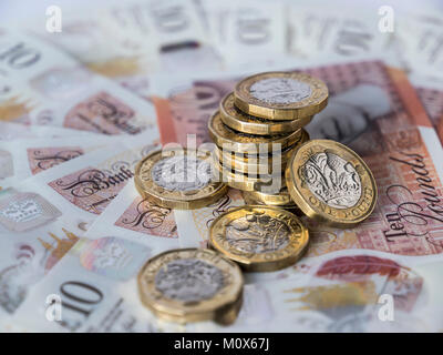 A pile of new British pound coins on a circular bed of new ten pound sterling notes Stock Photo