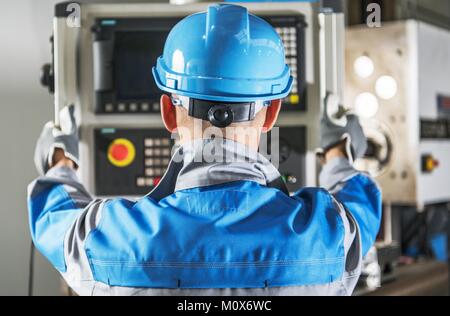 Caucasian CNC Operator in Front of Machine Operating Console. Metalworking Concept. Stock Photo