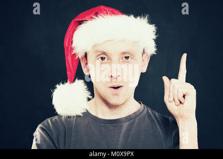 Christmas Man Pointing. Man in Santa Hat Stock Photo