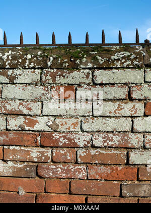 A brick wall with metal spikes on top Stock Photo