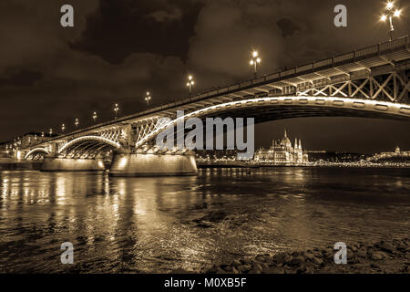 Night panorama of Budapest, Hungary, sepia tone. The illuminated Hungarian Parliament house in background, photographed from the Marguerite Bridge. Stock Photo