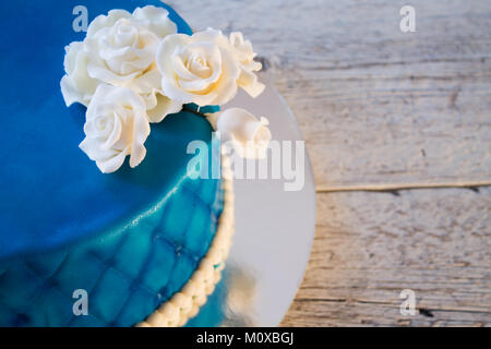 blue cake with white roses closeup on a light wooden background