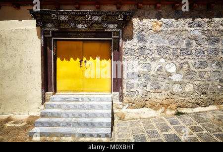 Old stone brick wall with yellow gate, China. Stock Photo