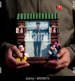 North Korean man showing his son picture serving in the army in a Mickey mouse frame, North Hamgyong Province, Jung Pyong Ri, North Korea Stock Photo