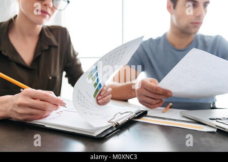 Cropped shot of concentrated busy young man and woman working at home with papers Stock Photo