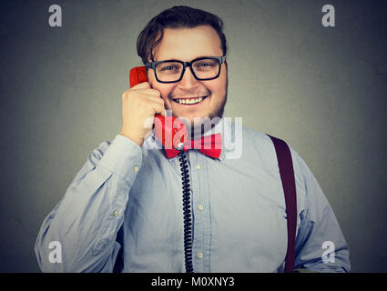 Young obese man looking delighted while speaking on phone and looking at camera. Stock Photo