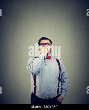 Young man in eyeglasses looking up and thinking thoroughly making important decision. Stock Photo