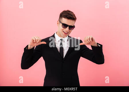 Young handsome man in official suit and sunglasses pointing at himself isolated over pink Stock Photo