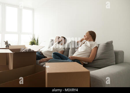 Young couple relaxing on couch just moved into new home Stock Photo