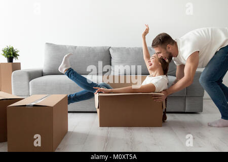 Happy couple having fun playing with cardboard box moving in Stock Photo