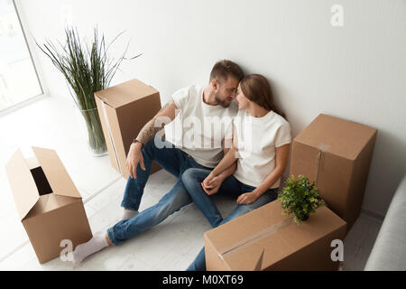 Young couple bonding sitting on the floor with moving boxes Stock Photo