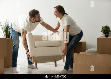 Young couple carrying chair together, placing furniture in new h Stock Photo
