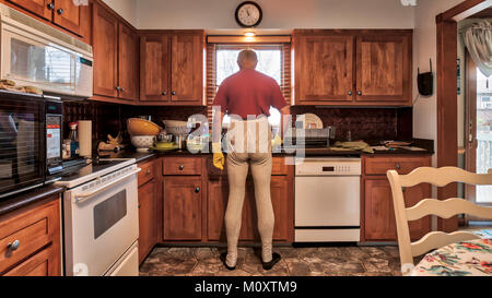A bachelor man doing the dishes in the kitchen sink. Stock Photo