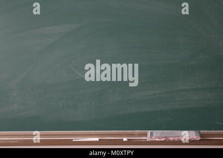 Green chalkboard with duster and chalk Stock Photo