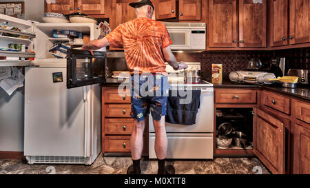 A bachelor man cooking himself a meal in the kitchen. Stock Photo
