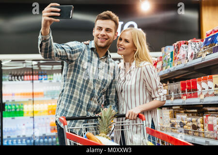 Happy couple taking a selfie at supermarket Stock Photo