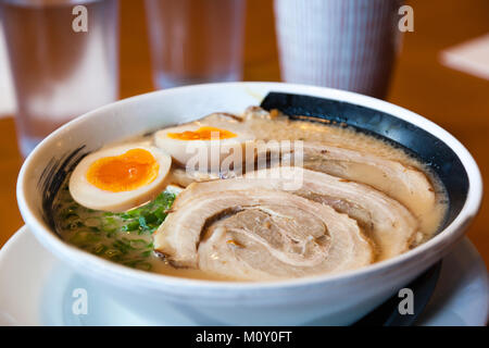 Close up of Japanese barbecued char siu pork ramen noodles with nitamago soft-boiled eggs in pork-bone broth and topped with scallions. Stock Photo