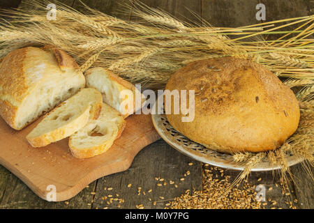 whole and sliced bread with ears and wheat grain on wooden background Stock Photo