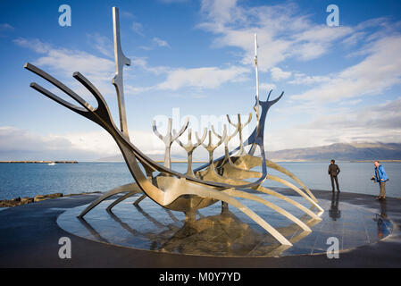 The Sun Voyager boat sculpture with people standing next to it on a partly cloudy day in Autumn, Reykjavik, Iceland Stock Photo