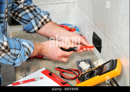 Electrician technician working on switches and sockets of a residential electrical system. Stock Photo