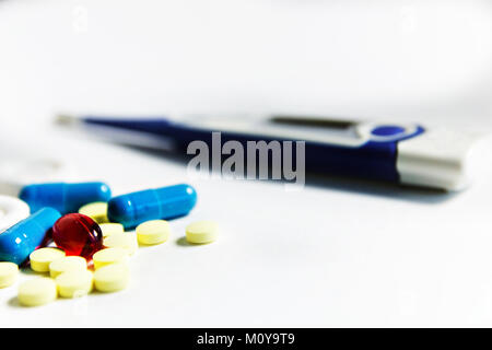 yellow, blue, red pills and the thermometer in the background. Stock Photo