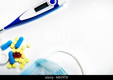 yellow, blue, red pills and the thermometer and mask, medicine isolated on white background. Stock Photo