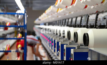 Female Textile Worker at Work.  Automated Yarn Spinning Machines. Row of automated machines for yarn manufacturing. Stock Photo