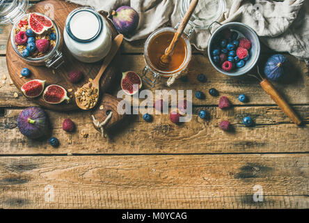 Healthy vegan breakfast. Oatmeal granola with bottled almond milk, honey, fresh fruit and berries over rustic wooden table background, copy space, top Stock Photo