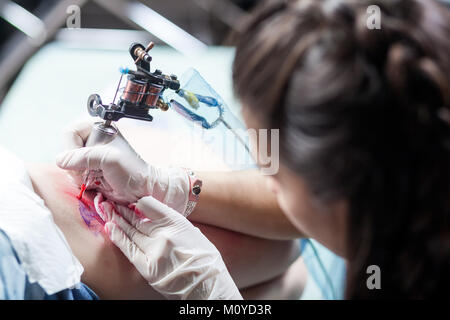 Beautiful dark-haired woman tattoo artist drawing a tattoo for a tattoo, close-up, bottom view Stock Photo