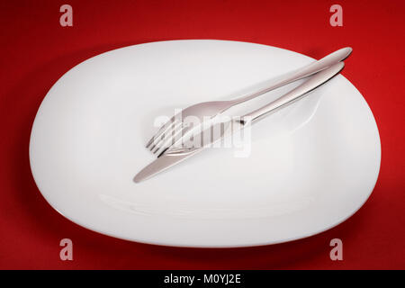 White empty square plate with fork and knife on red table Stock Photo