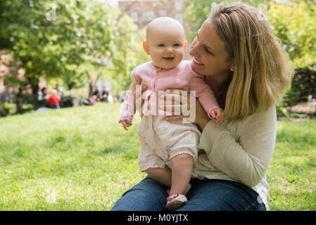 Portrait of Caucasian mother holding baby daughter in park Stock Photo