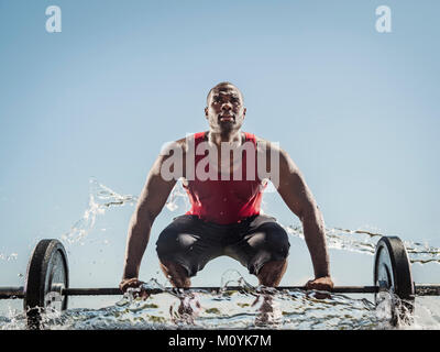 Water spraying on black man preparing for lifting barbell Stock Photo