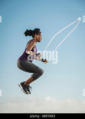 Black woman jumping rope in sky Stock Photo