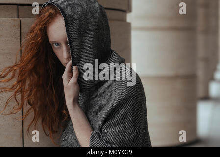 Caucasian woman hiding face behind hood Stock Photo