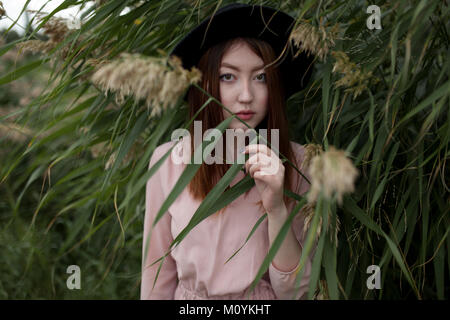 Asian woman standing in foliage Stock Photo