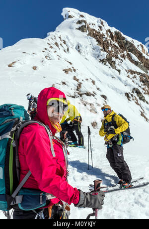 Ski mountaineers roped together for safety from crevasses use synthetic skins on skis to climb uphill; Antarctica; Wilhemina Bay; Nansen Island Stock Photo