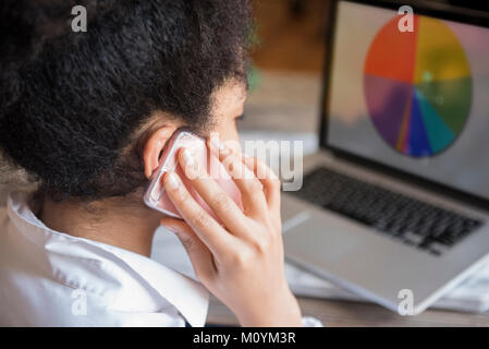 African American woman talking on cell phone and using laptop Stock Photo
