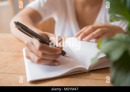 Hands of African American woman writing in journal Stock Photo
