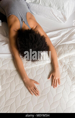 African American woman stretching back on bed Stock Photo