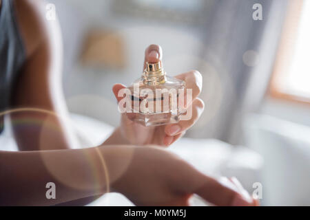 African American woman spraying perfume on wrist Stock Photo