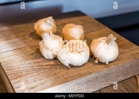 Several heads of garlic on a wooden cutting  board Stock Photo