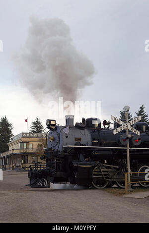 Historic steam train at railway crossing in Heritage Park Historical Village Stock Photo