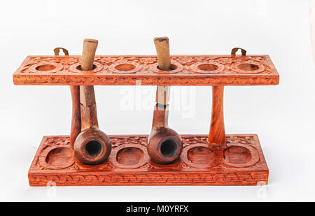 Beautufully carved antique wooden pipe stand with two pipes Stock Photo