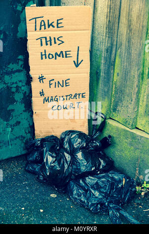 Dog mess / dog poo thrown away in black plastic bags with aa warning sign left by an objector to this practice. (93) Stock Photo