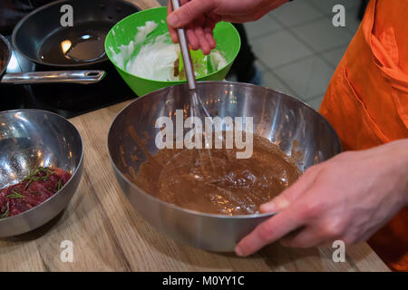 Hands mix chocolate dough with whisk Stock Photo
