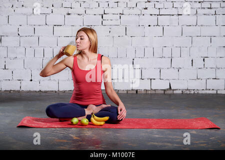 Yoga Vegetarianism. Girl drinks smoothies. Woman having a yelloy juice in the hall after her yoga practice. concept of healthy life. Stock Photo