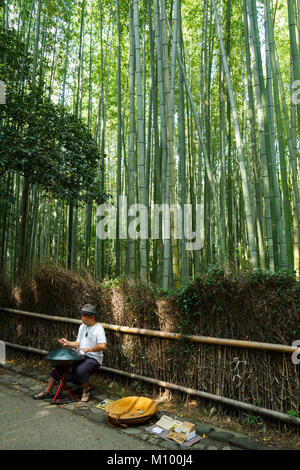 Japanese musician playing a percussion metallic hang in the bamboo forest in Arashiyama, Kyoto, Japan Stock Photo