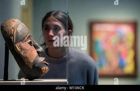 Hamburg, Germany. 25th Jan, 2018. Hamburg, Germany, 25 January 2018. A woman looking at a mask from Gabon/Angola in the exhibition 'Karl Schmidt-Rottluff: expressive, magical, foreign' in the Bucerius Kunstforum in Hamburg, Germany, 25 January 2018. The works by the artist from the 'Die Bruecke' group of artists will be on display in Hamburg between 27 January and 21 March 2018. ATTENTION EDITORS: EDITORIAL USE ONLY IN CONNECTION WITH CURRENT REPORTING/MANDATORY CREDITS. Credit: Axel Heimken/dpa/Alamy Live News Stock Photo