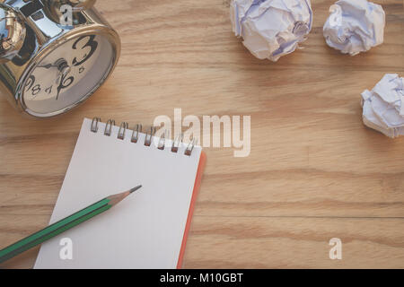 Business Creative and Idea Concept : Used green pencil put on notebook with white crumpled paper ball put on wooden table. (Selective focus) Stock Photo