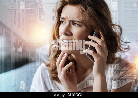 Confused woman having a conversation on phone Stock Photo